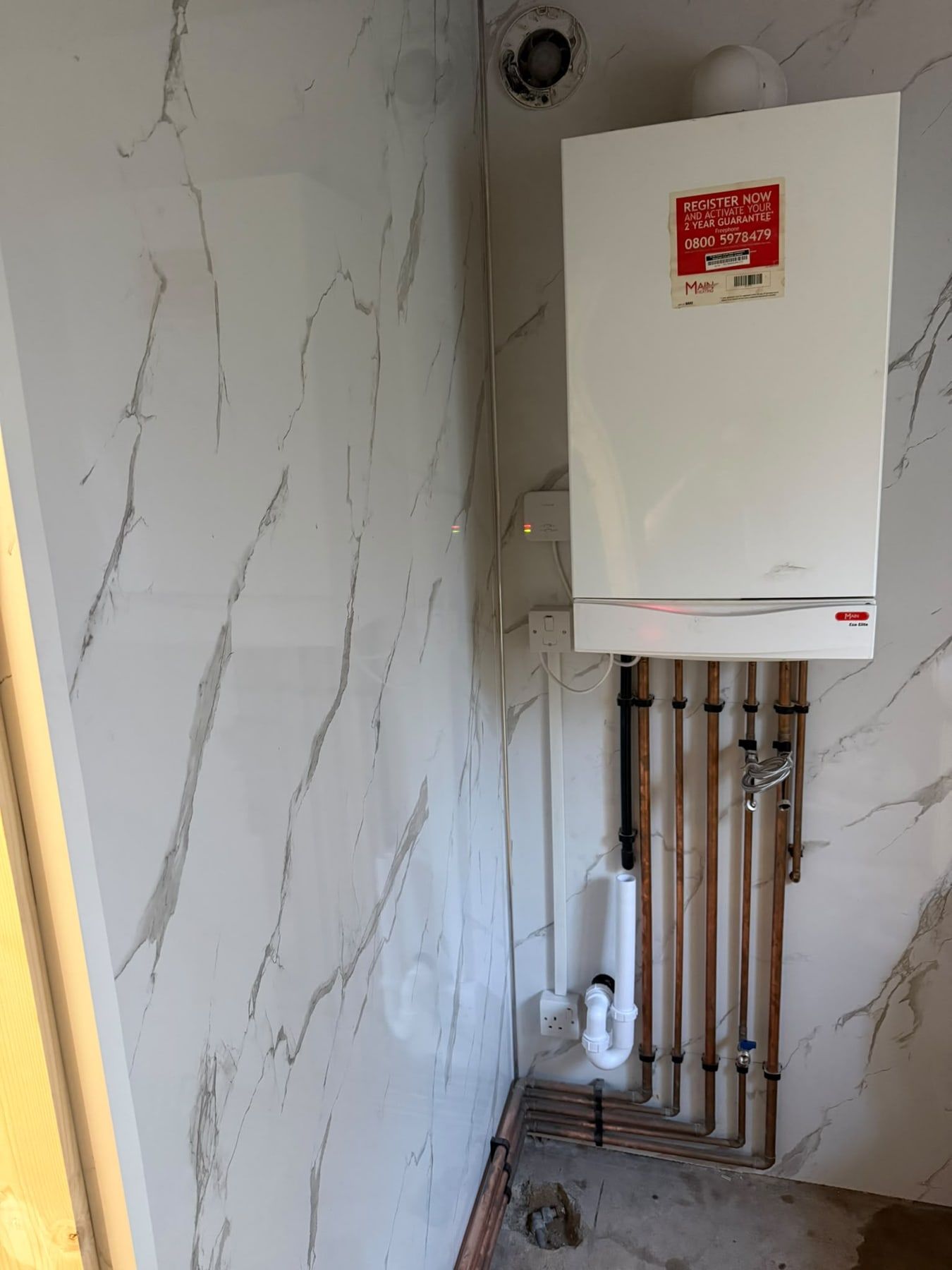 Combi boiler on a marble-effect wall with copper pipework