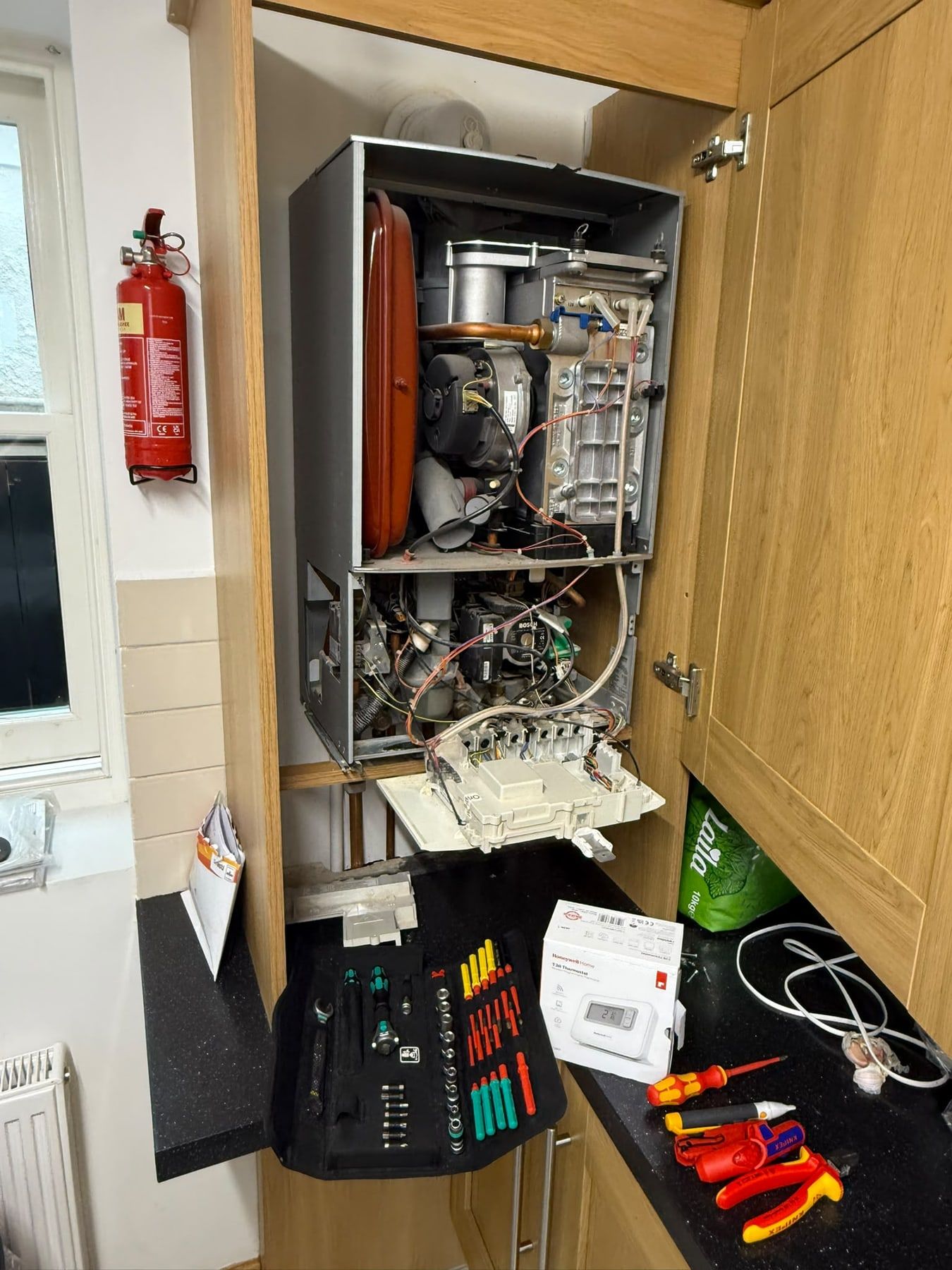 Boiler with the case off during a repair, tools laid out on the worktop