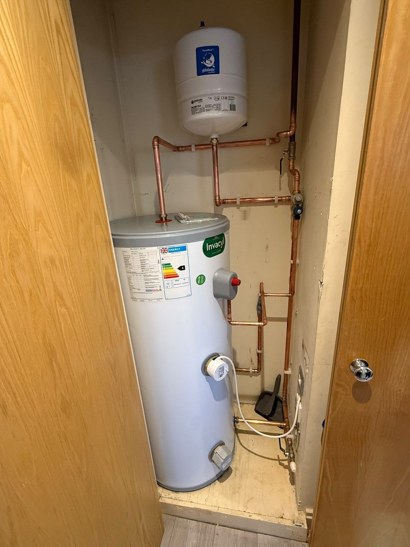 New unvented hot water cylinder with copper pipework in a cupboard