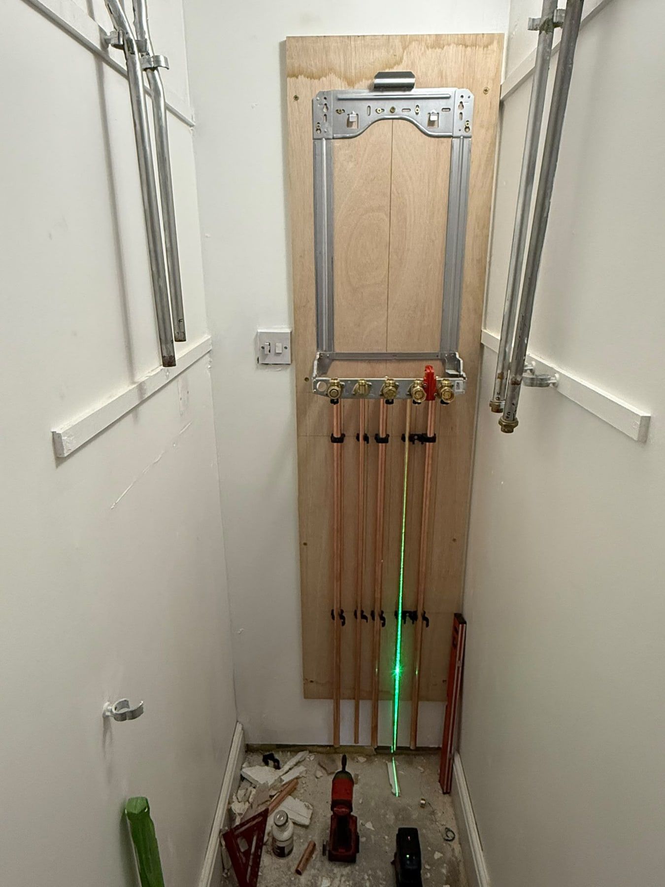 Pipework first fix on a timber board with a laser level line