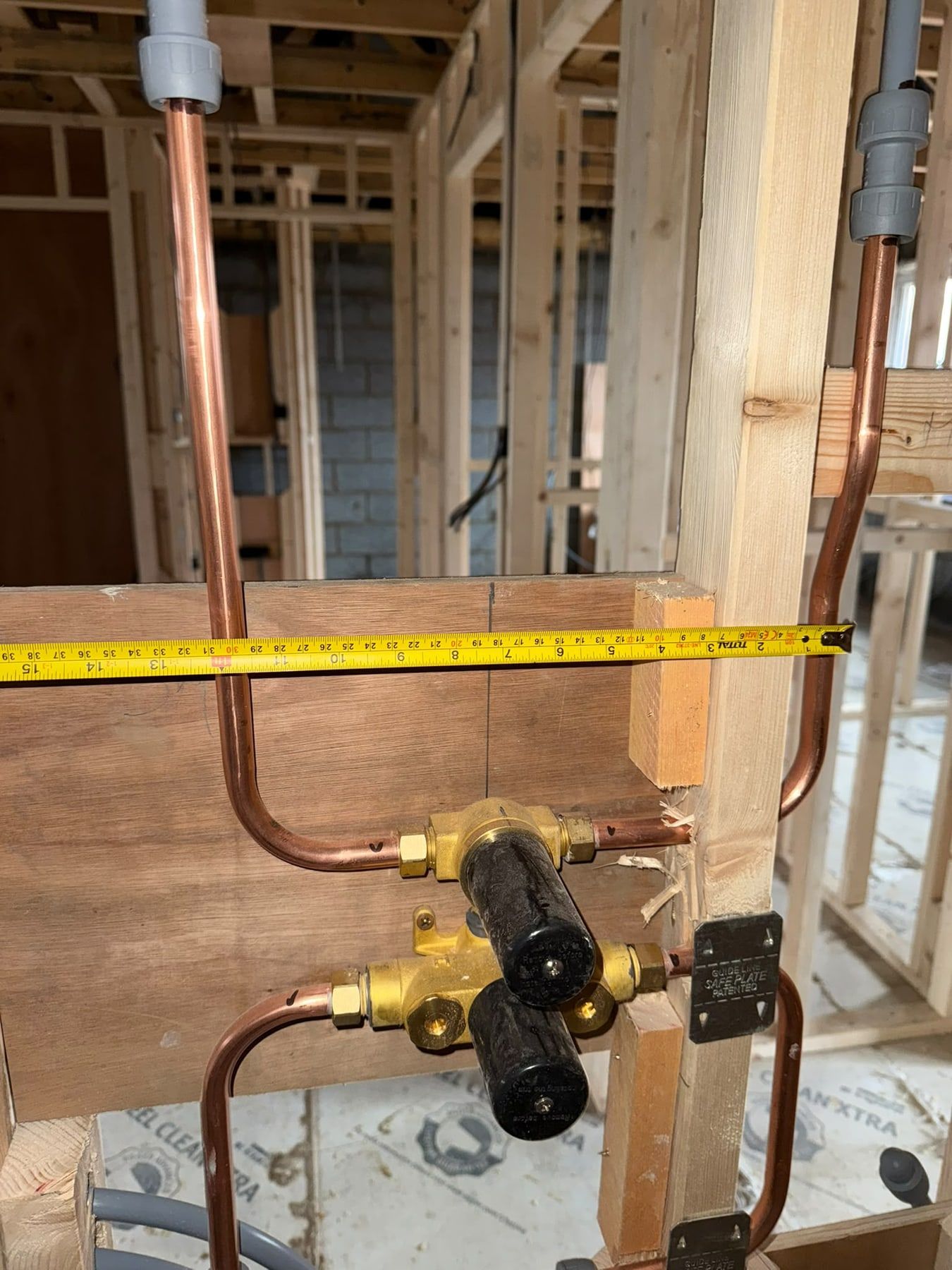 First fix copper pipework and mixer valve in a timber stud wall, with a tape measure
