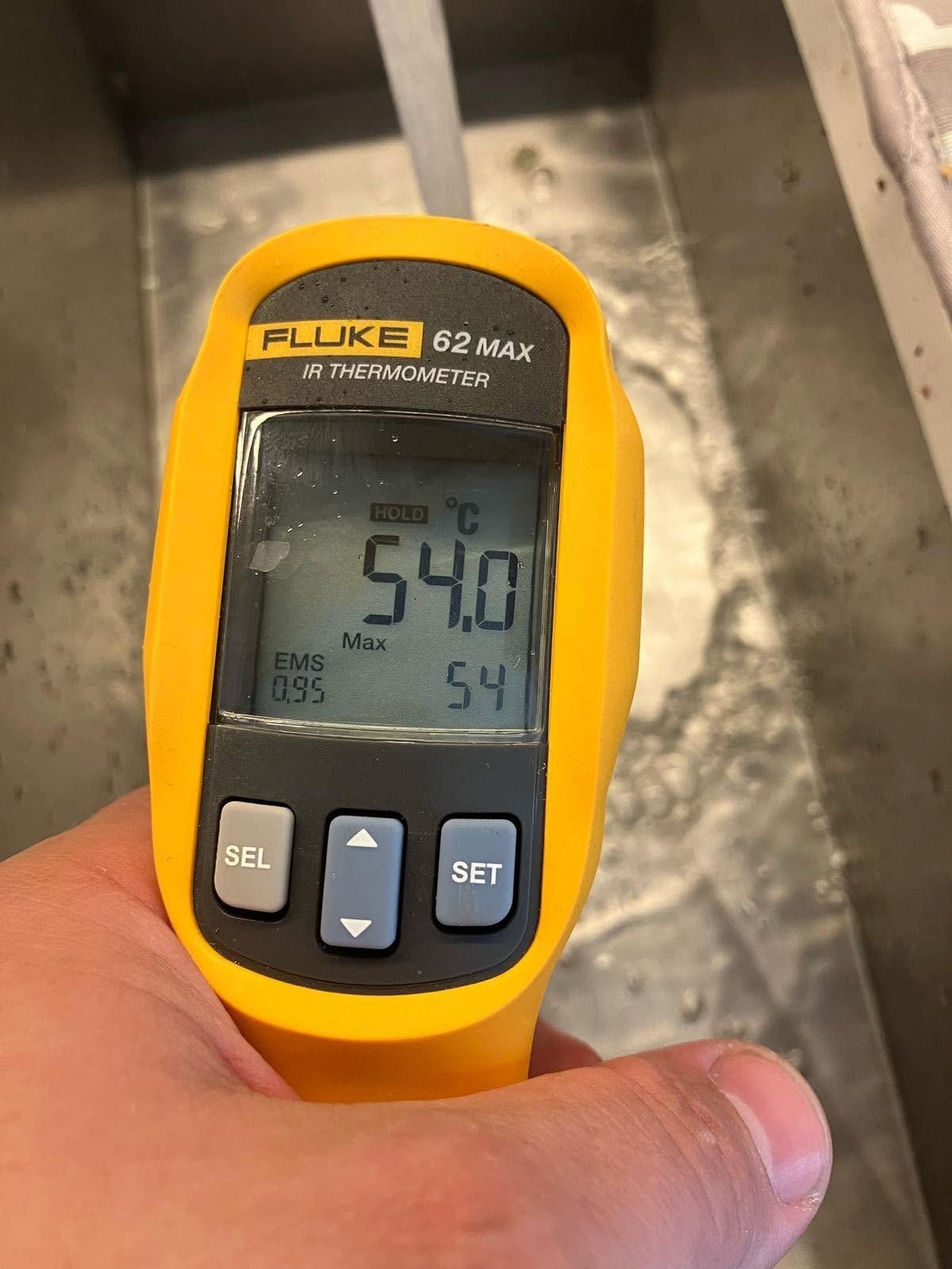Infrared thermometer reading 54 degrees on a heating pipe