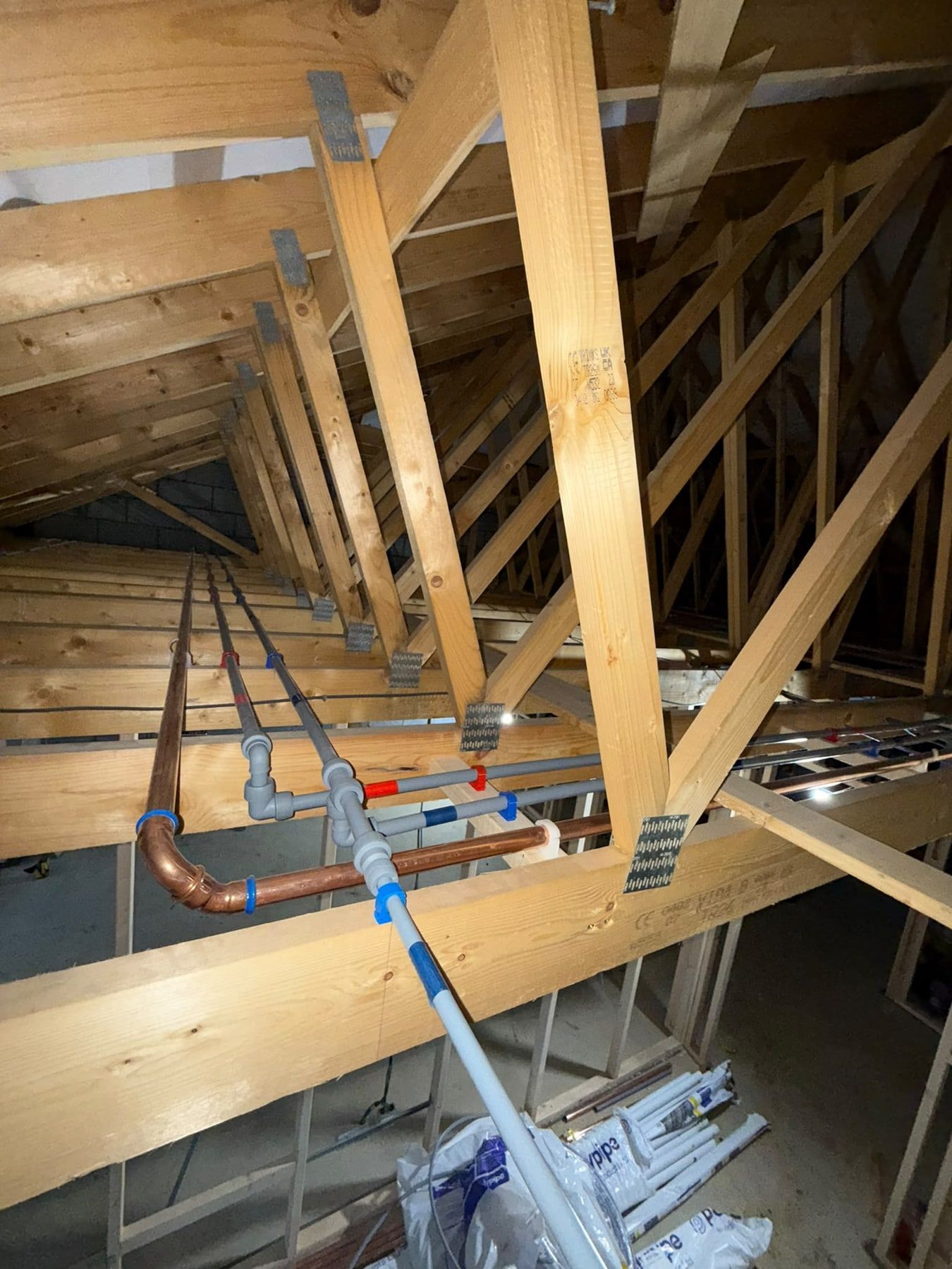 Heating pipework run through a loft between timber trusses